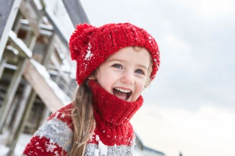 Lachendes Mädchen mit roter Mütze in Winterlandschaft