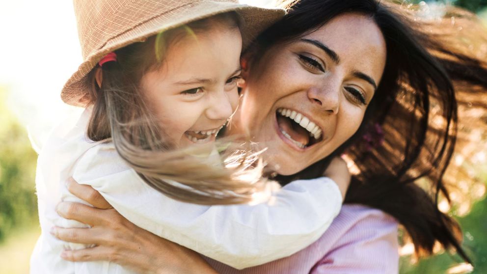 Une maman et sa fille qu’elle porte dans les bras sourient devant l’appareil photo