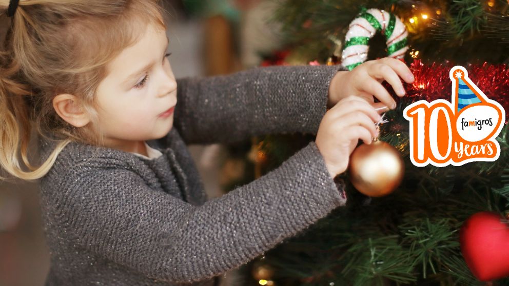 Kleines Mädchen hängt eine Kugel an den Weihnachtsbaum