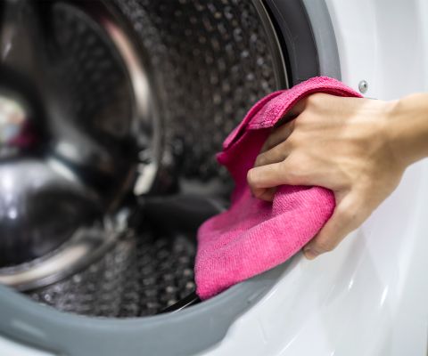 Una lavatrice viene pulita con un panno