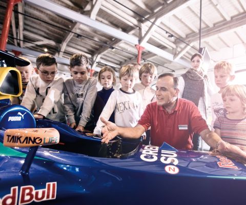Kinder stehen um ein Formel-1-Auto herum