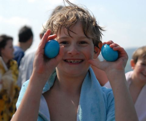 Junge in Badetuch gehüllt hält zwei blaue Eier in der Hand