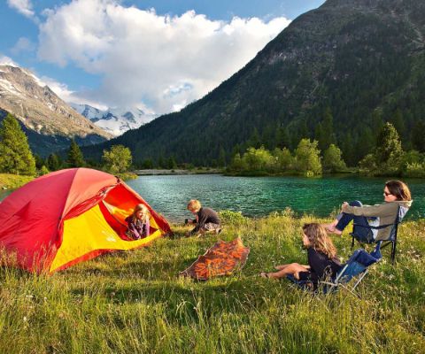 Famiglia con una tenda rossa davanti a un lago in montagna