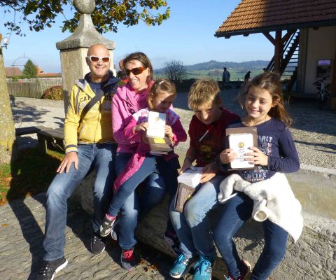 Famille devant la fromagerie de dégustation de l’Emmentaler, les enfants tiennent la boîte de détective dans leurs mains