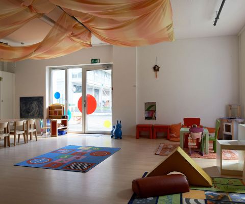 Spielzimmer mit Teppich, Kinderstühle und Kisten