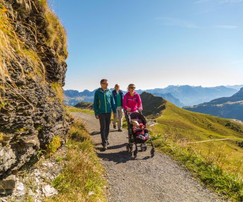 Familie mit Kinderwagen wandert in den Bergen