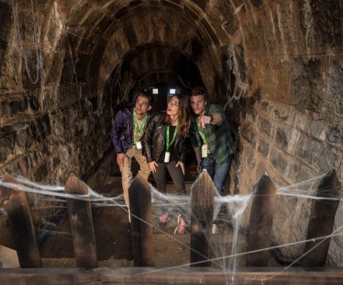 Trois jeunes personnes dans un caveau avec des toiles d'araignées