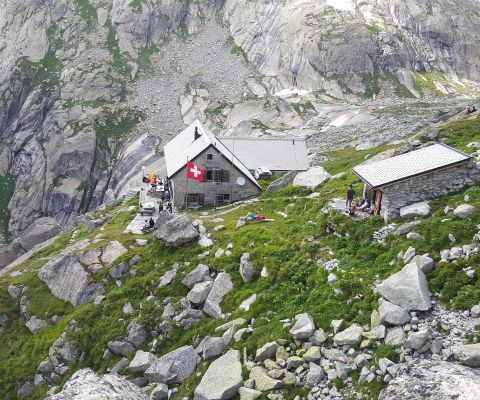 Randonneur devant la cabane de Gelmer avec vue imprenable sur les montagnes en arrière-plan