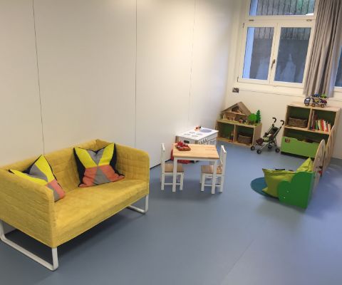 Kinderspielzimmer mit gelbem Sofa, Spielzeug und Kindertisch