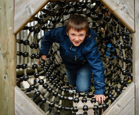 Un bambino gattona attraverso un tunnel di funi