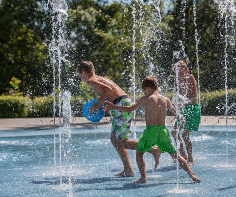 Tre bambini giocano sulla riva del laghetto del Gurten con le numerose fontane