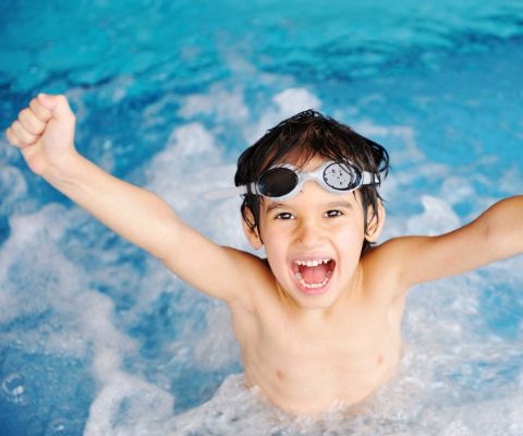 Glücklicher Junge mit Taucherbrille im Schwimmbad