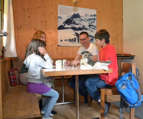 Familie sitzt am Tisch mit einem Husky-Plüschtier
