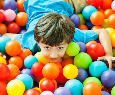 Un ragazzino in un mare di palline colorate