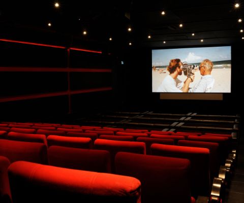 Kinosaal mit leeren, roten Sitzen und Leinwand
