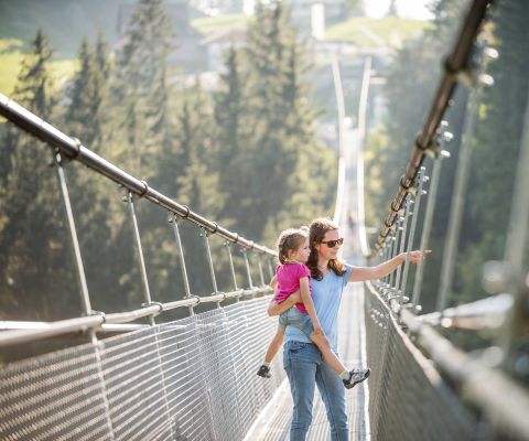 Mutter und Tochter läuft über lange Hängebrücke im Sattel-Hochstuckli
