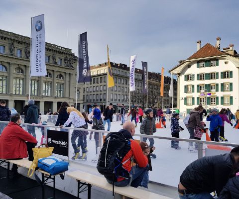 Kunsteisbahn auf dem Bundesplatz in Bern mit historischer Häuserkulisse