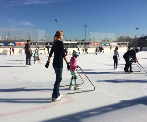 Kinder und Erwachsene fahren mit Schlittschuhen auf einem Eisfeld im Freien 