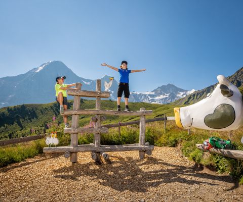 Deux garçons jouent sur une structure d’escalade devant la vache en bois «Liselotte»