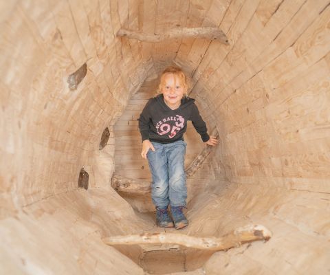 Ein Kind geht durch eine Höhle in dem Murmeli-Bau in Lenk
