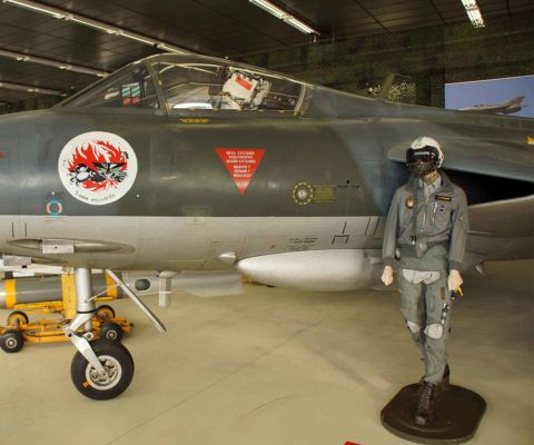 Un jet militare e davanti una bambola in uniforme da pilota