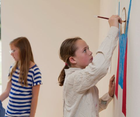 Mädchen malt Bild an einer Wand