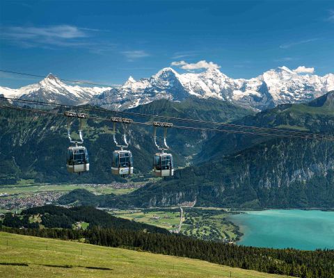 Trois télécabines de téléphérique du Niederhorn devant des montagnes et un lac