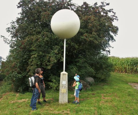 Una famiglia ammira la statua di un pianeta sulla Via dei pianeti di Effretikon