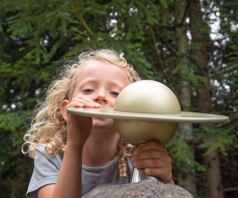 Blondes Mädchen mit einer Statue des Planeten Saturns