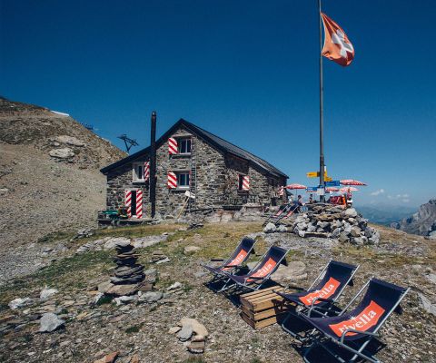 Cabane de montagne conviviale avec drapeau suisse et chaises longues
