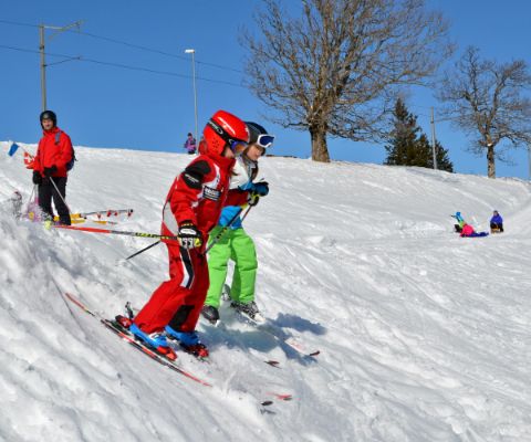 Bambini scendono un pendio con gli sci