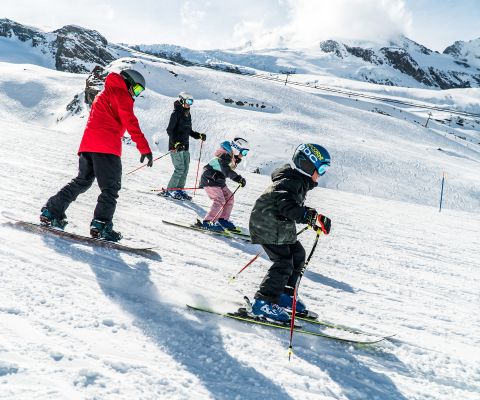 Toute une famille faisant du ski ou du snowboard.