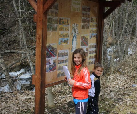 Due bambini in piedi davanti a un grande cartello escursionistico