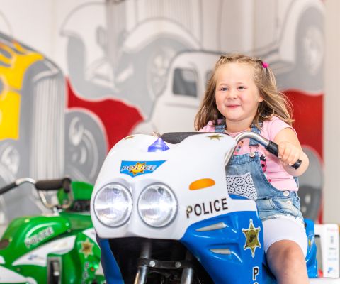 Una bambina è seduta sull'auto della polizia