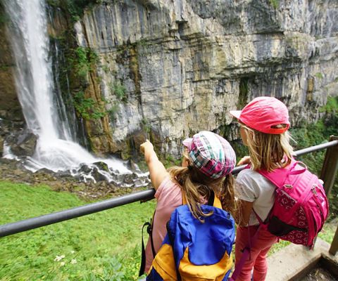 Zwei Mädchen schauen und zeigen auf einen Wasserfall