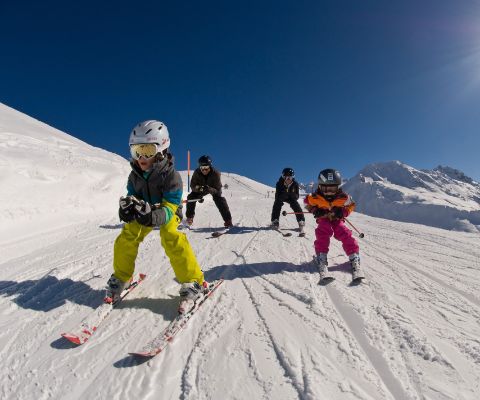 Vier Kinder fahren Ski an einem herrlichen sonnigen Tag