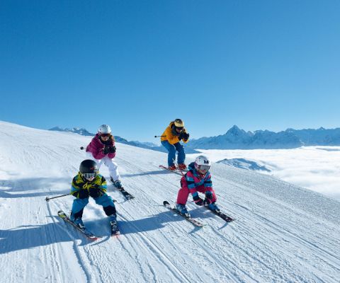 Familie fährt auf Skiern im Schuss den Hang hinunter