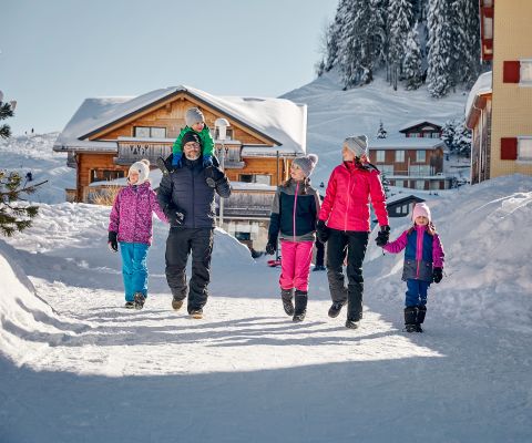 Familie beim gemütlichen Winterspaziergang auf der Ringstrasse rund ums Dorf Stoos