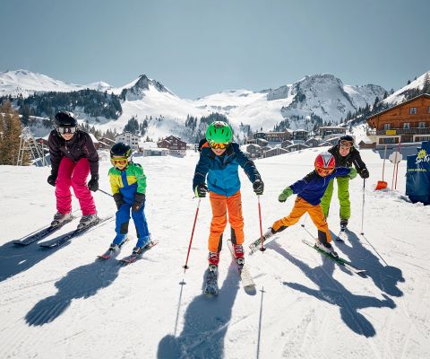Familie auf Skiern auf einem sonnigen Hochplateau im Skigebiet Stoos 