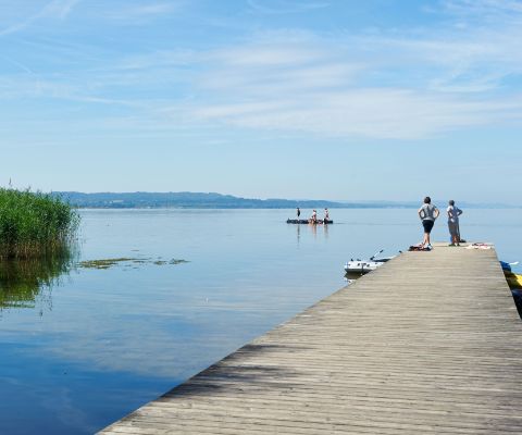 Famille sur un ponton en bois regardant le lac avec un îlot de baignade