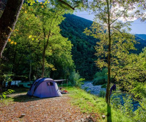 Zelt unter Bäumen mit Blick auf den Fluss