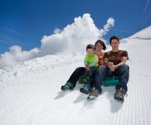 Famille avec un petit enfant faisant de la luge sur un versant enneigé