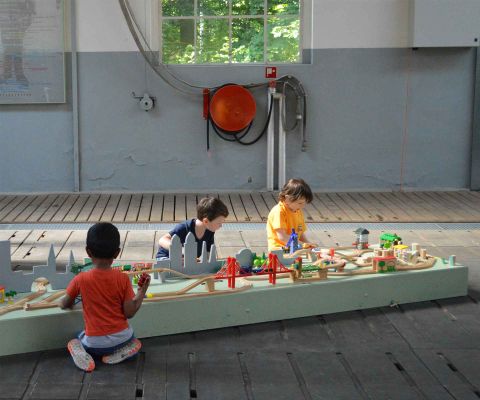 Trois enfants jouent avec un petit train en bois