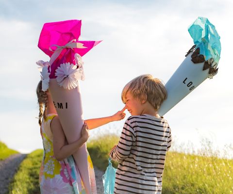 2 enfants avec leur cornet surprise, décorés de fleurs en papier de soie