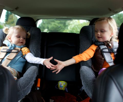 Deux enfants dans leur siège d’enfant sur la banquette arrière d’une voiture