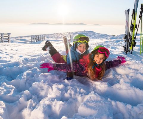 Zwei Kinder in Ski-Ausrüstung haben Spass im Schnee
