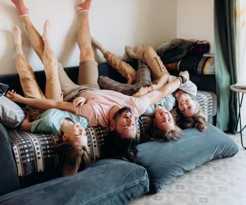 Una famiglia è sdraiata a testa in giù su un divano