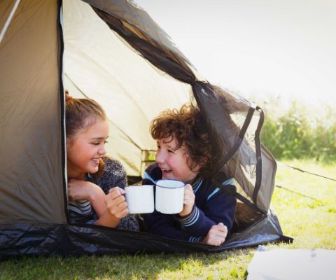 Kinder im Zelt mit einer Tasse in der Hand