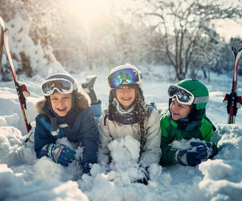 Trois enfants sont allongés côte à côte dans la neige