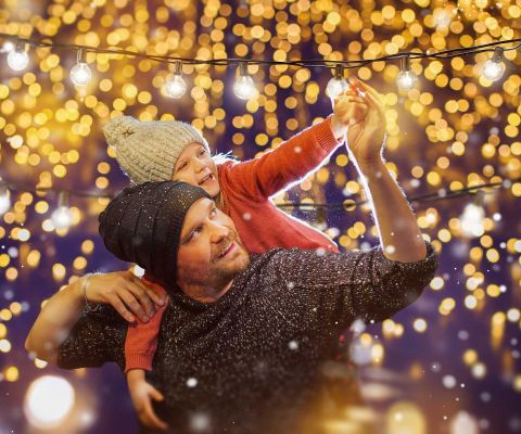 Père et fille sous les guirlandes lumineuses de Noël